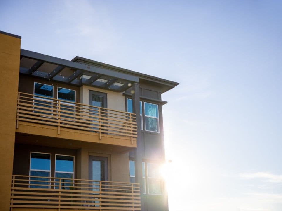 A modern apartment building with balconies, in late afternoon sun